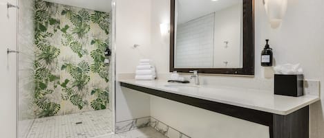 A modern bathroom with a shower, a large mirror, and a vanity with a bottle of lotion.