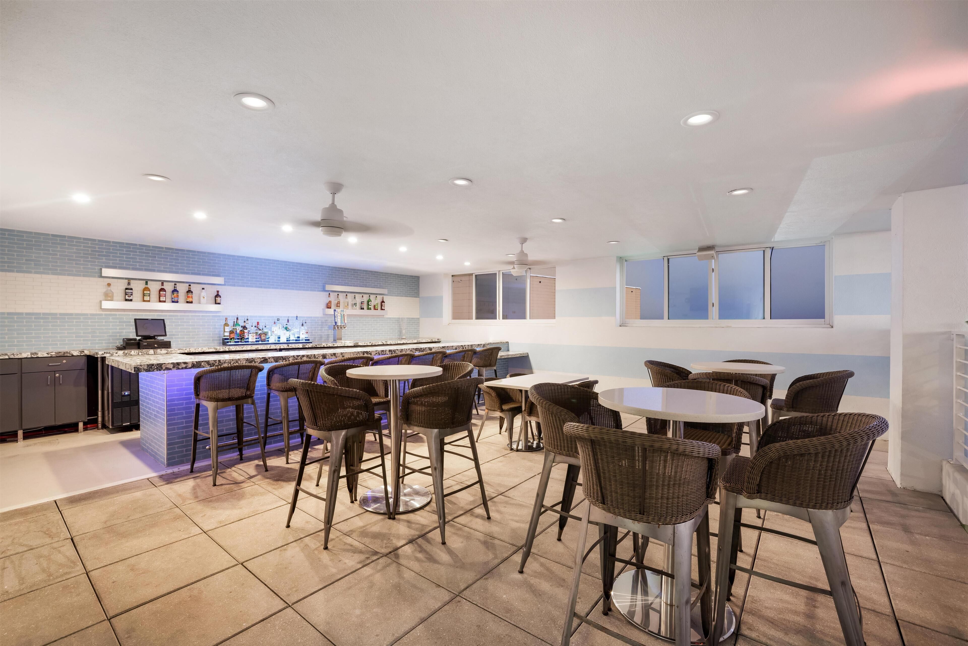 Une cuisine moderne dotée d’un bar, de tabourets de bar et d’un coin repas avec des tables et des chaises rondes.
