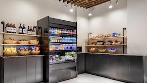 Een moderne hotel receptie met een automaat voor drankjes, manden met snacks en flessen water.