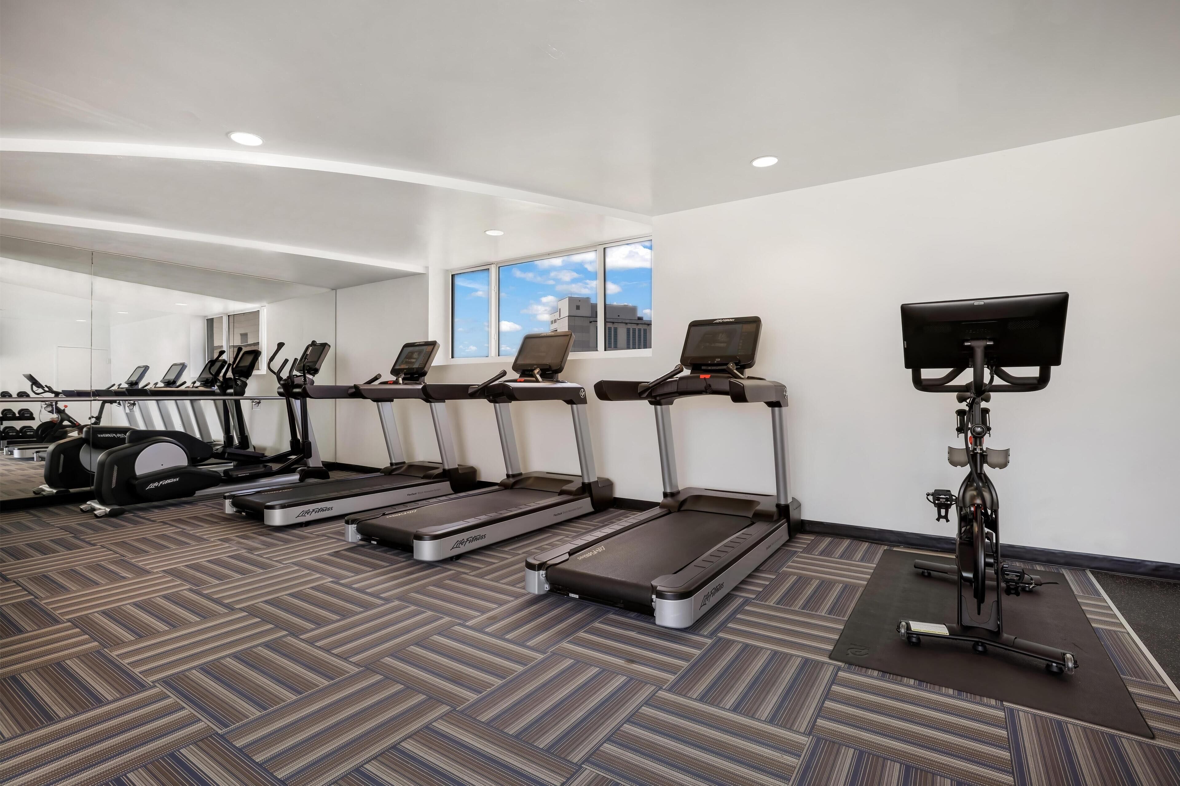 A gym with treadmills, a stationary bike, and a rowing machine.