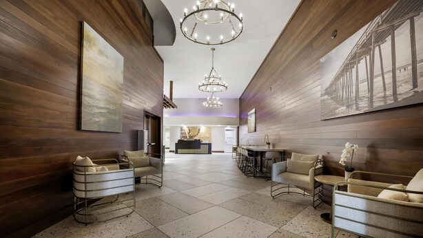 Een ruime lobby met een hoge plafond, een kroonluchter en een receptiebalie op de achtergrond.