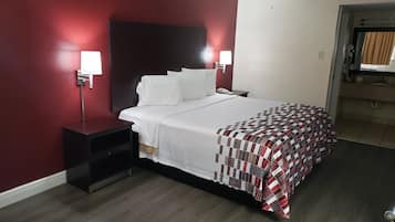 Une chambre d’hôtel avec un lit, des tables de chevet, un mur rouge et une fenêtre.