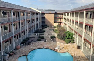 Un patio con piscina, rodeado de edificios de varios pisos con balcones.