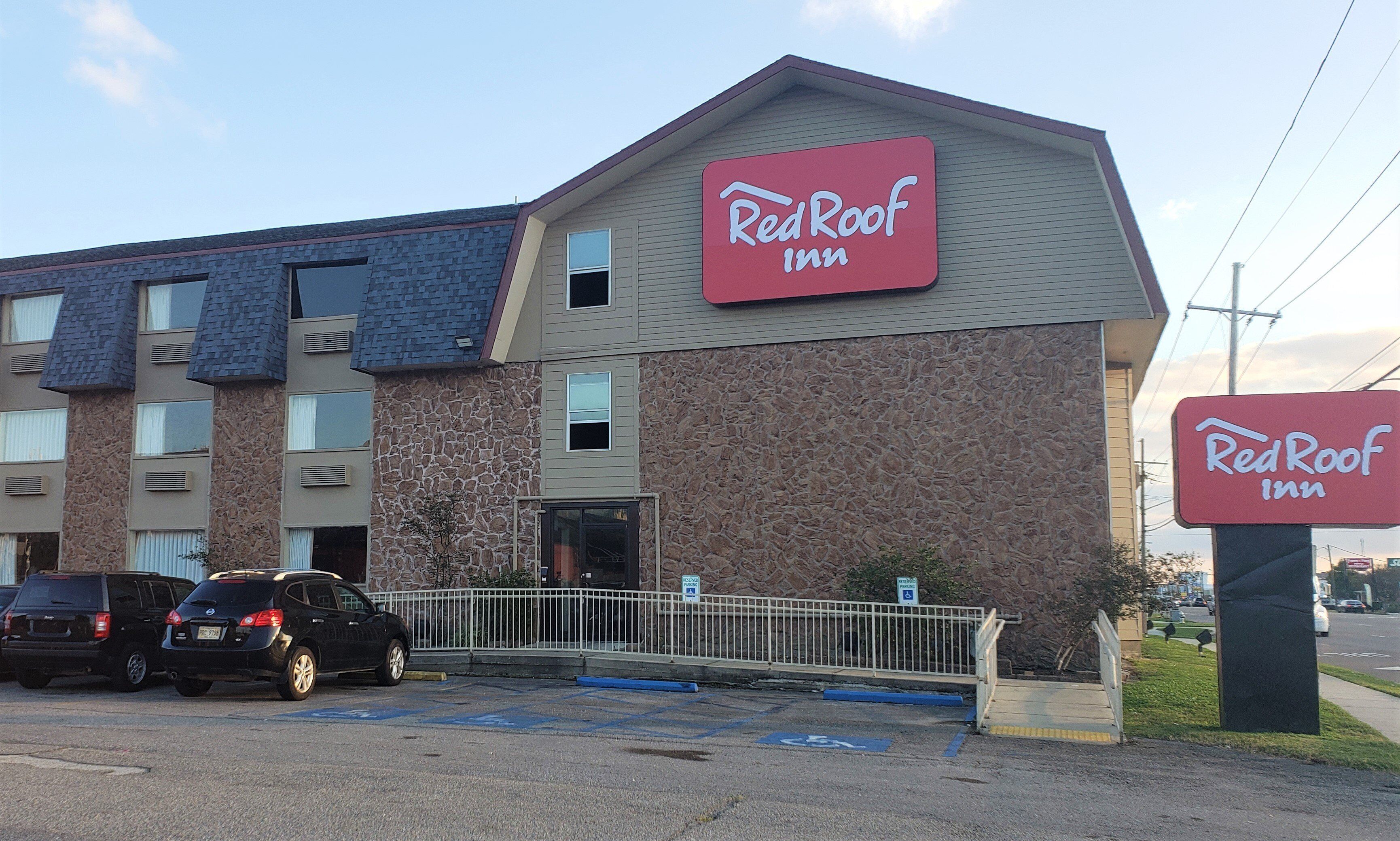 A RedRoof Inn building with a stone facade, multiple windows, and a parking lot with cars.
