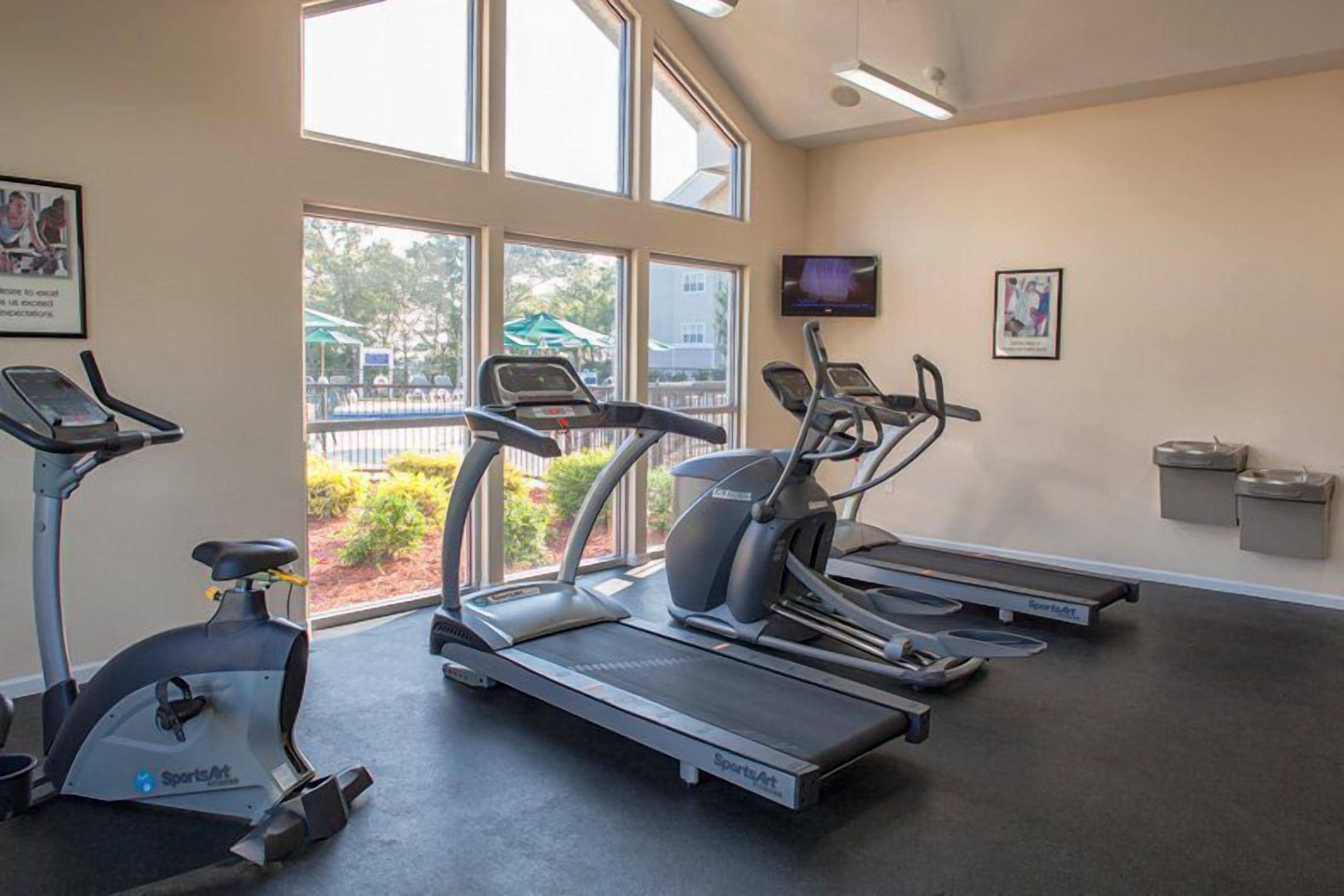 Een sportschool met loopbanden, hometrainers en een roeimachine.