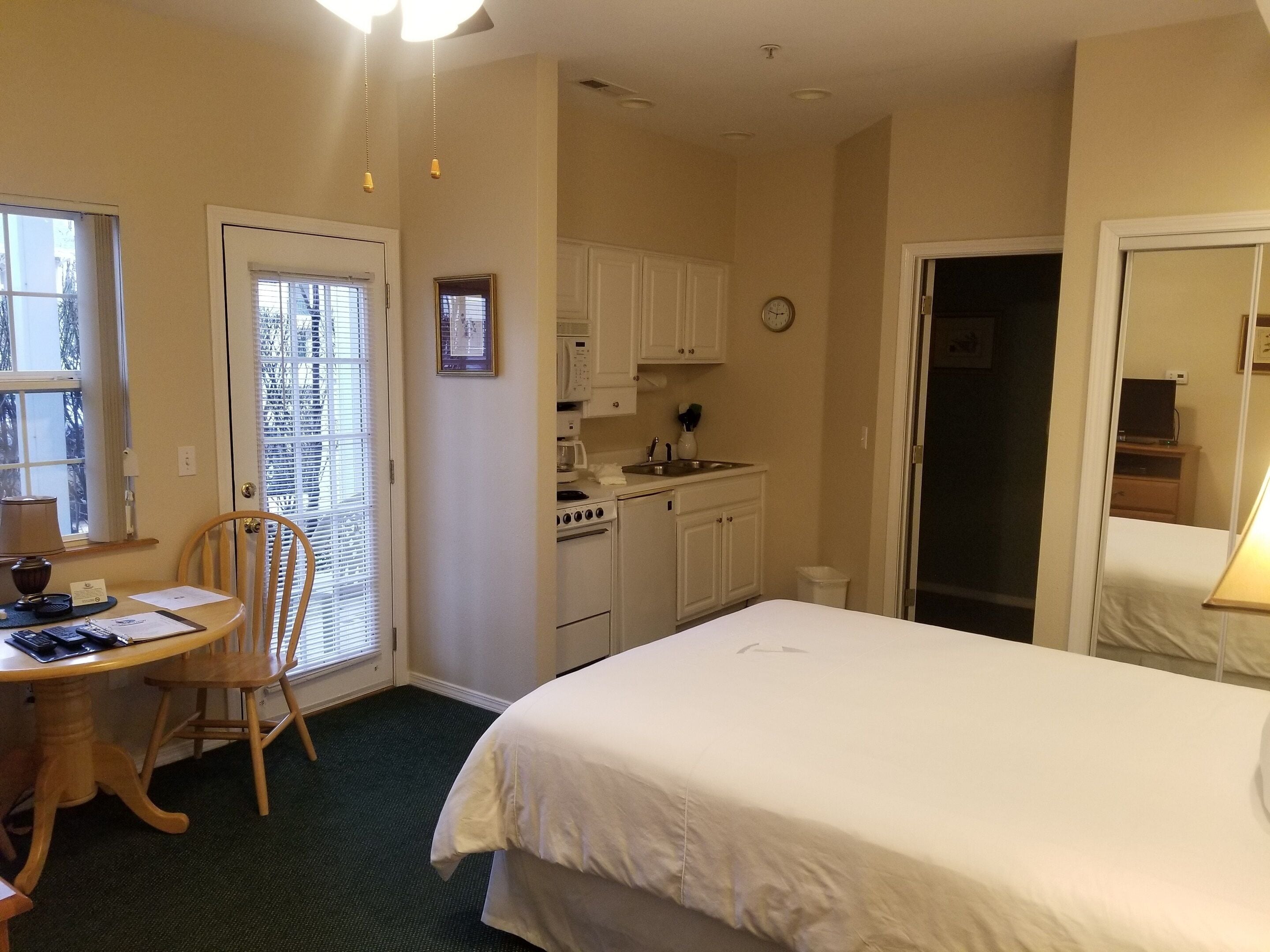 Een hotelkamer met een bed, een eettafel met stoelen, een kitchenette en een badkamer.