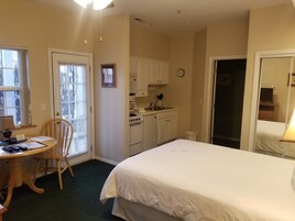 Ein Hotelzimmer mit Bett, Esstisch mit Stühlen, Küchenzeile und Bad.