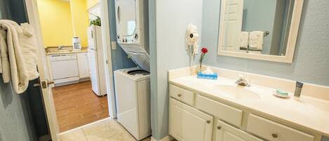 A bathroom with a sink, mirror, and a hairdryer on the wall.