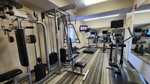 A gym with various exercise equipment, a television, and a mirrored wall. - Candlewood Suites Greenville NC by IHG (Greenville)