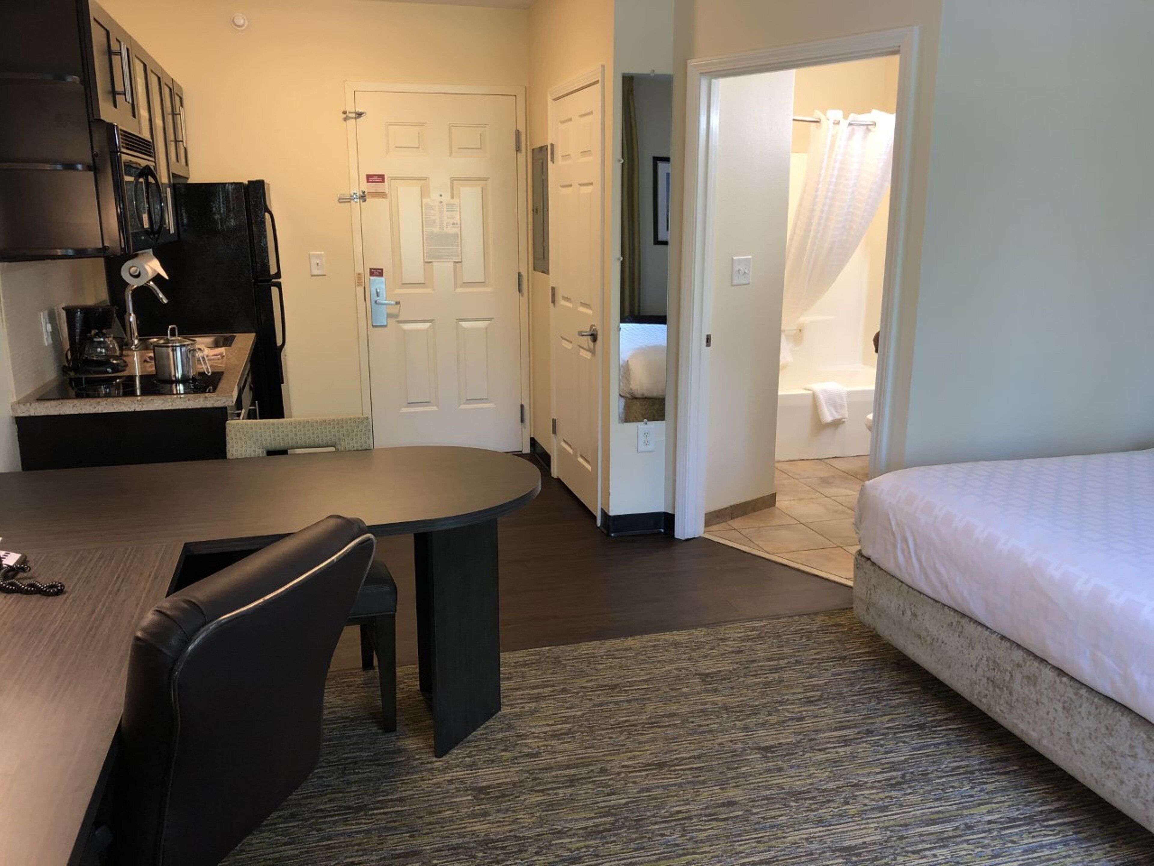 Habitación de hotel compacta con cama, kitchenette pequeña, zona de comedor y baño.