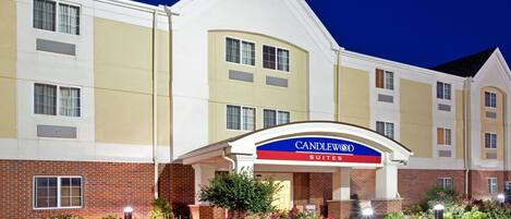 A hotel with a prominent 'CANDLEWOOD SUITES' sign, featuring a brick facade and a landscaped entrance.