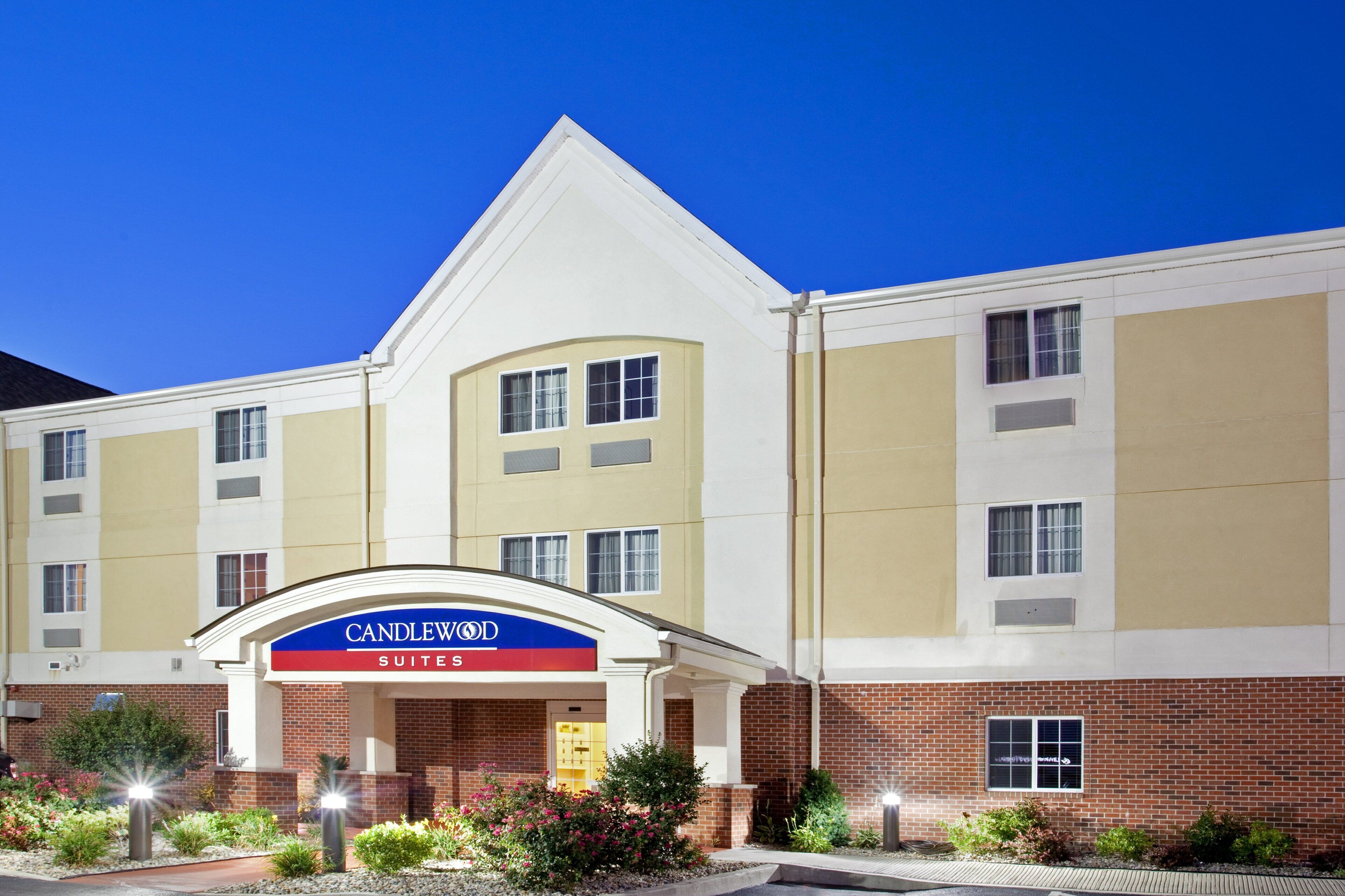 Um hotel com uma placa grande de 'CANDLEWOOD SUITES', várias janelas e fachada de tijolos.