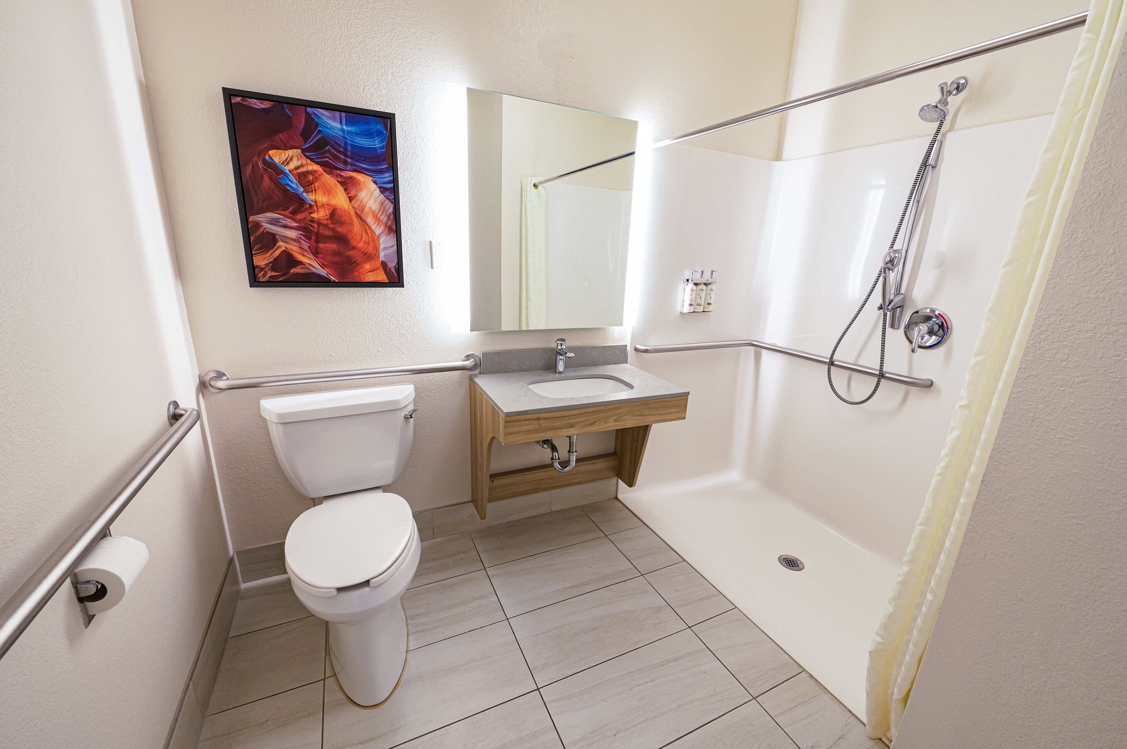 Une salle de bain avec des toilettes, un lavabo, une douche et un tableau accroché au mur.