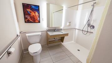 Une salle de bain avec des toilettes, un lavabo, une douche et un tableau accroché au mur.