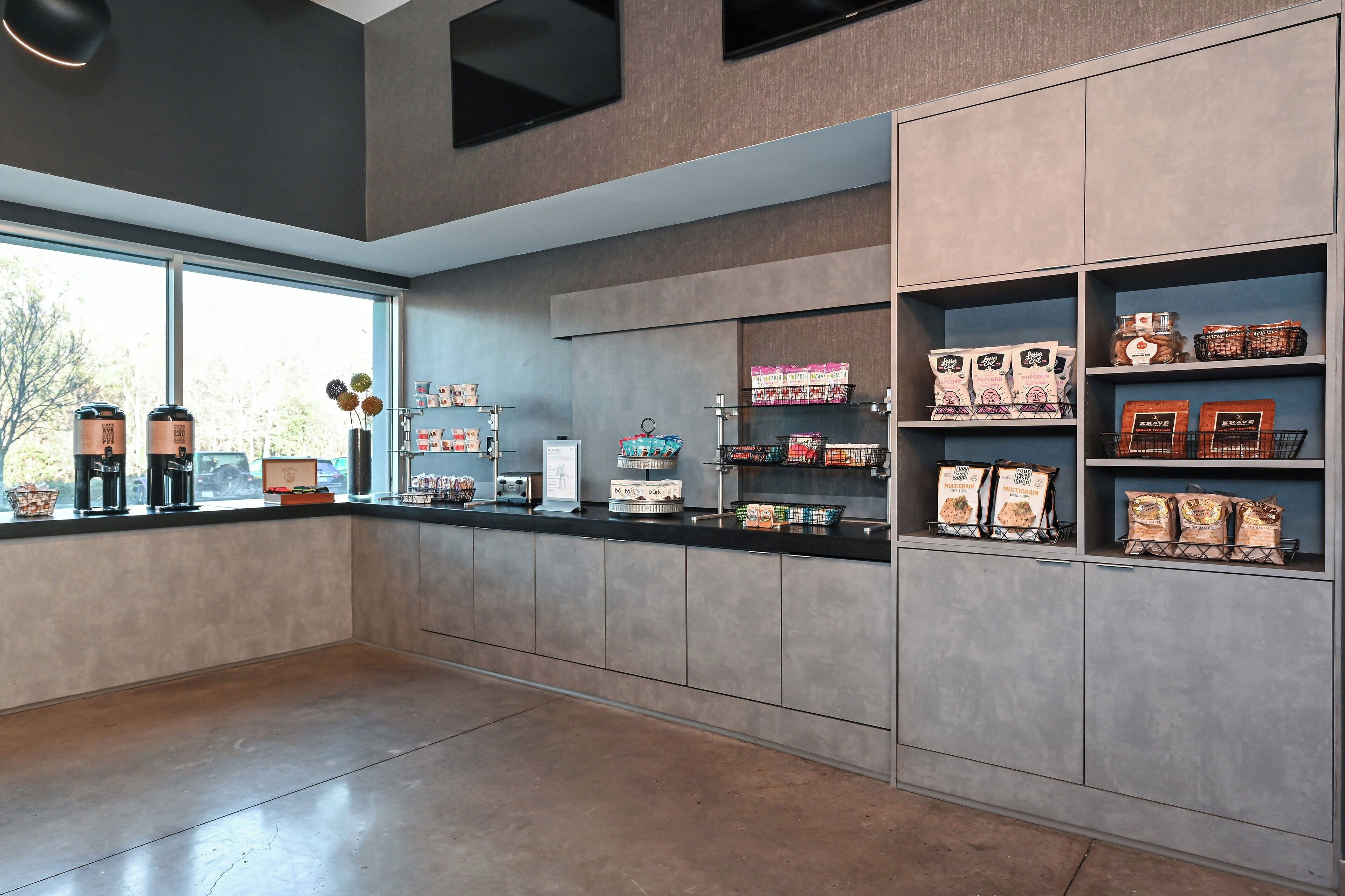 A modern kitchen with built-in appliances, a large window, and shelves stocked with coffee and tea products.
