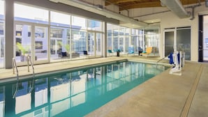 An indoor swimming pool with clear glass walls, a wooden ceiling, and a lifeguard chair. - Aloft by Marriott Charleston Airport & Convention Center (North Charleston)