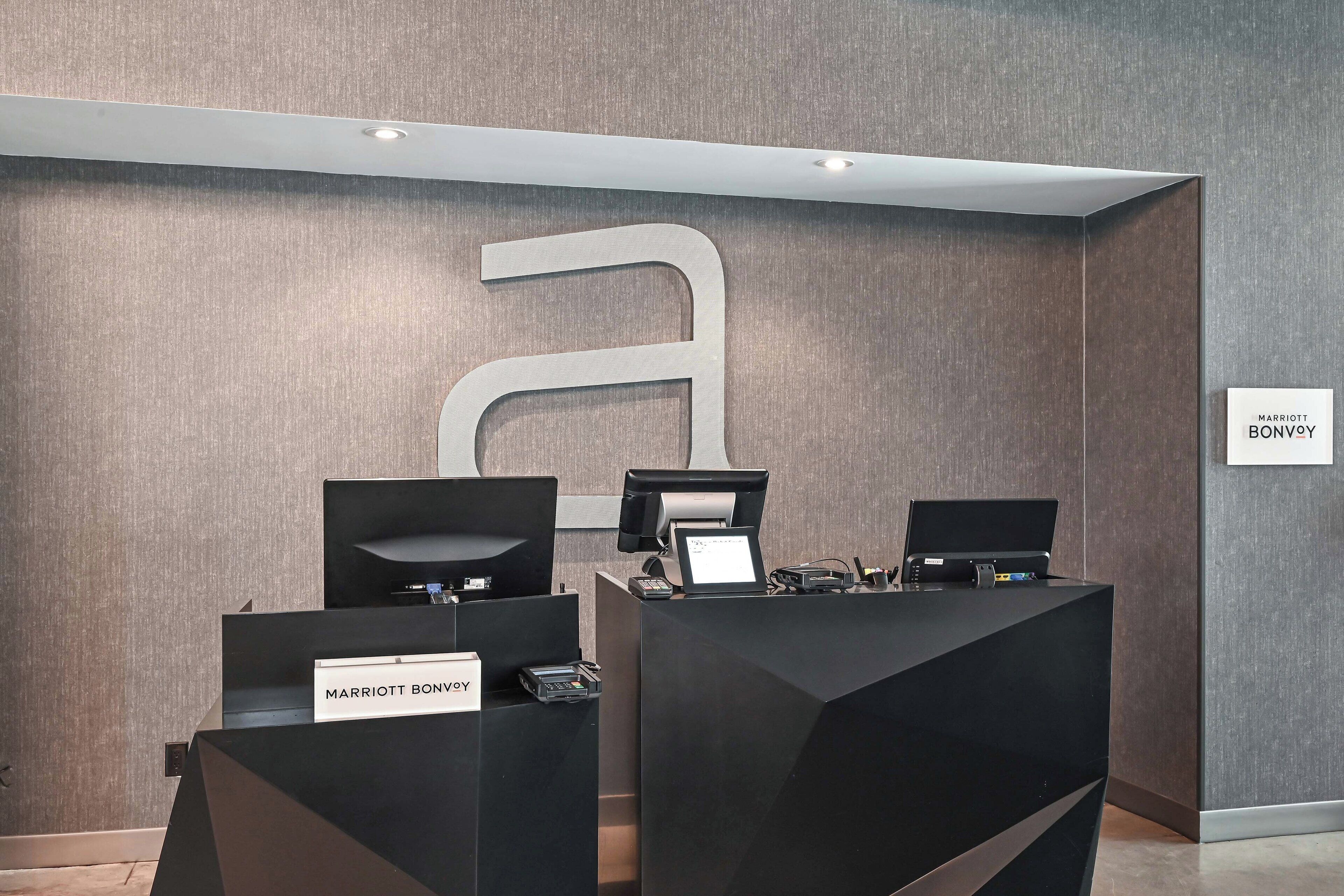 A reception area with two black reception desks, each labeled "Marriott Bonvoy."