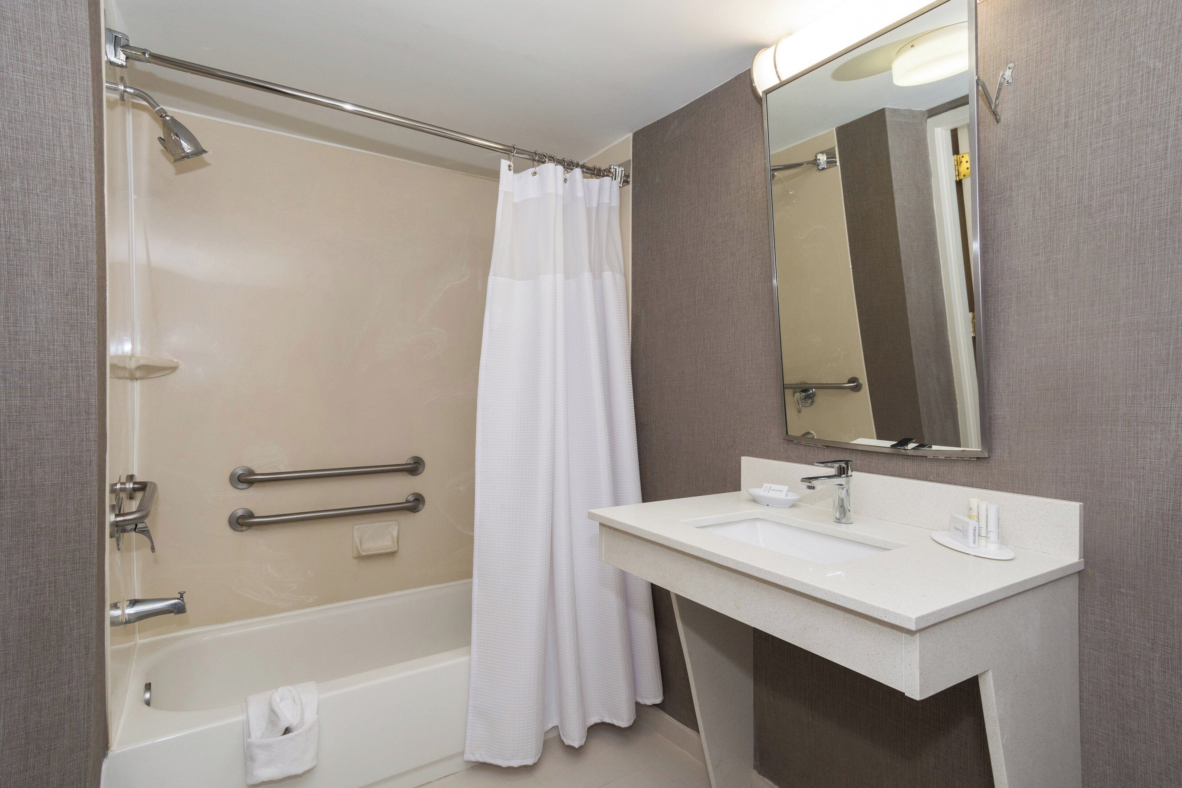 A modern bathroom with a bathtub, shower, and a vanity with a mirror.
