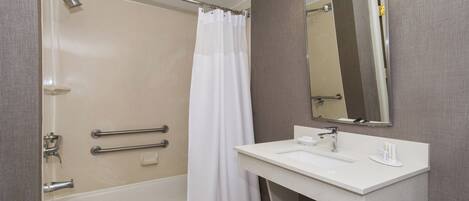 A modern bathroom with a bathtub, shower, and a vanity with a mirror.