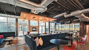 A modern lounge area with seating, tables, and a bar. - Aloft by Marriott Charleston Airport & Convention Center (North Charleston)