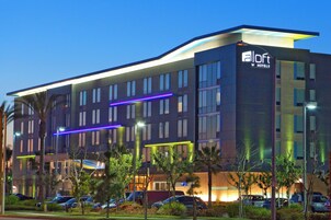 Un moderno edificio de hotel con varios pisos, ventanas amplias y un cartel llamativo que dice 'Loft W Hotels'.