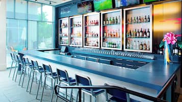 Una zona de bar con una barra larga, estantes con varias botellas y taburetes.