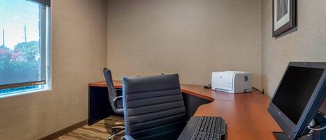 Uma sala de conferências com uma janela grande, uma cadeira de escritório preta, uma mesa com computador e impressora.