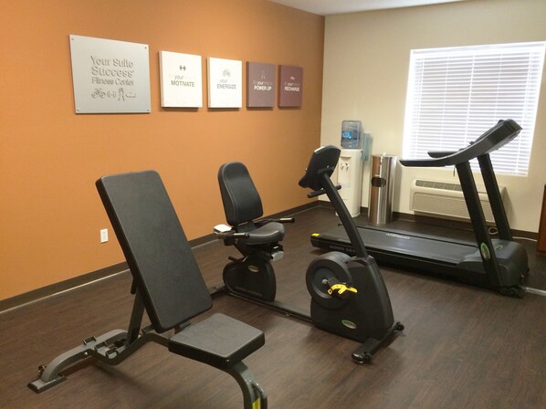 Une salle de sport équipée d’un vélo d’appartement, d’un tapis de course et d’un banc de musculation.