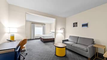 Habitación de hotel con cama, sofá, escritorio, silla y una pequeña mesa redonda.