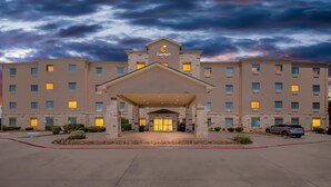 A hotel with a central entrance, multiple floors, and a stormy sky. - Comfort Suites San Antonio North - Stone Oak (San Antonio)
