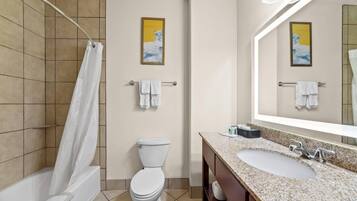 Un baño con ducha, inodoro, lavamanos y toallero.