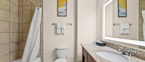 A bathroom with a shower, toilet, sink, and towel rack.