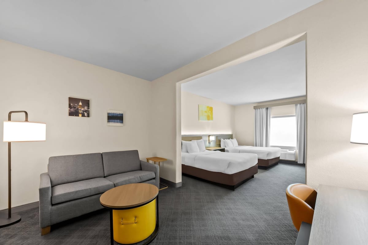 Ein Hotelzimmer mit einer Couch, einem runden Tisch, einem Bett und einem Sessel.