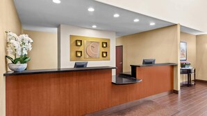 A reception area with wooden reception desks, a wall-mounted clock, and a potted plant. - Comfort Suites San Antonio North - Stone Oak (San Antonio)