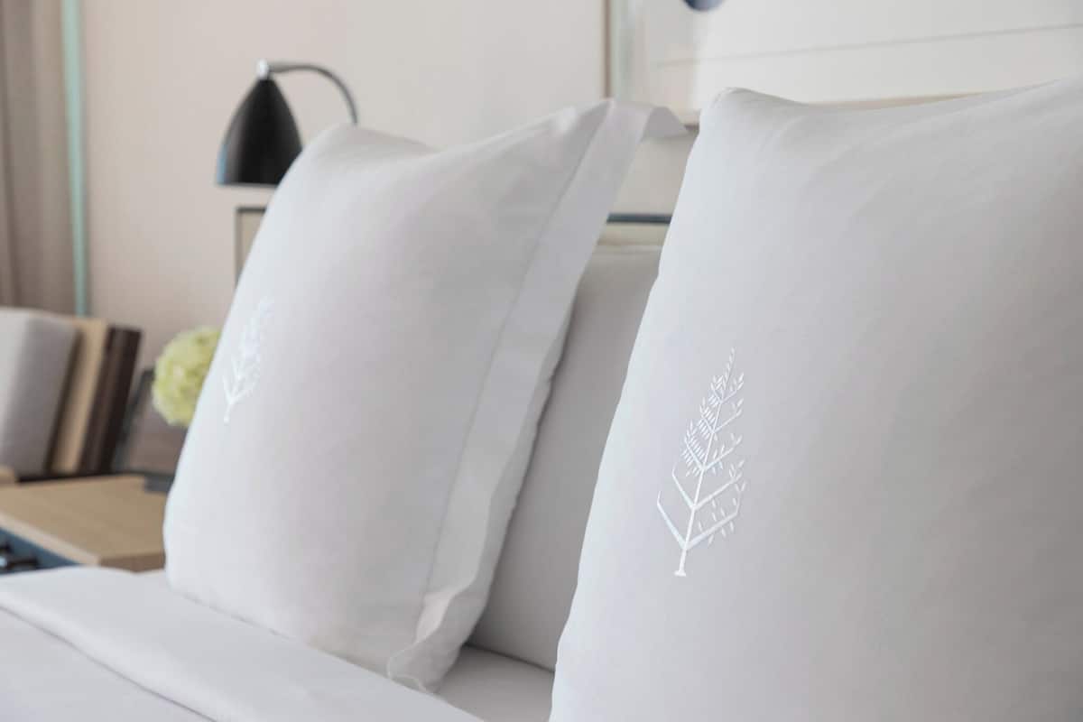 A bed with white pillows featuring a leaf design.