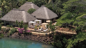 Un resort con strutture a tetto di paglia, una piscina e rigogliosa vegetazione.