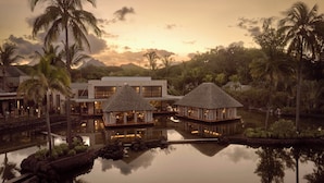 Un resort con piscina, bungalow sull'acqua e palme.