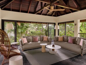 A modern living room with a large sofa, a round coffee table, and a wicker chair.