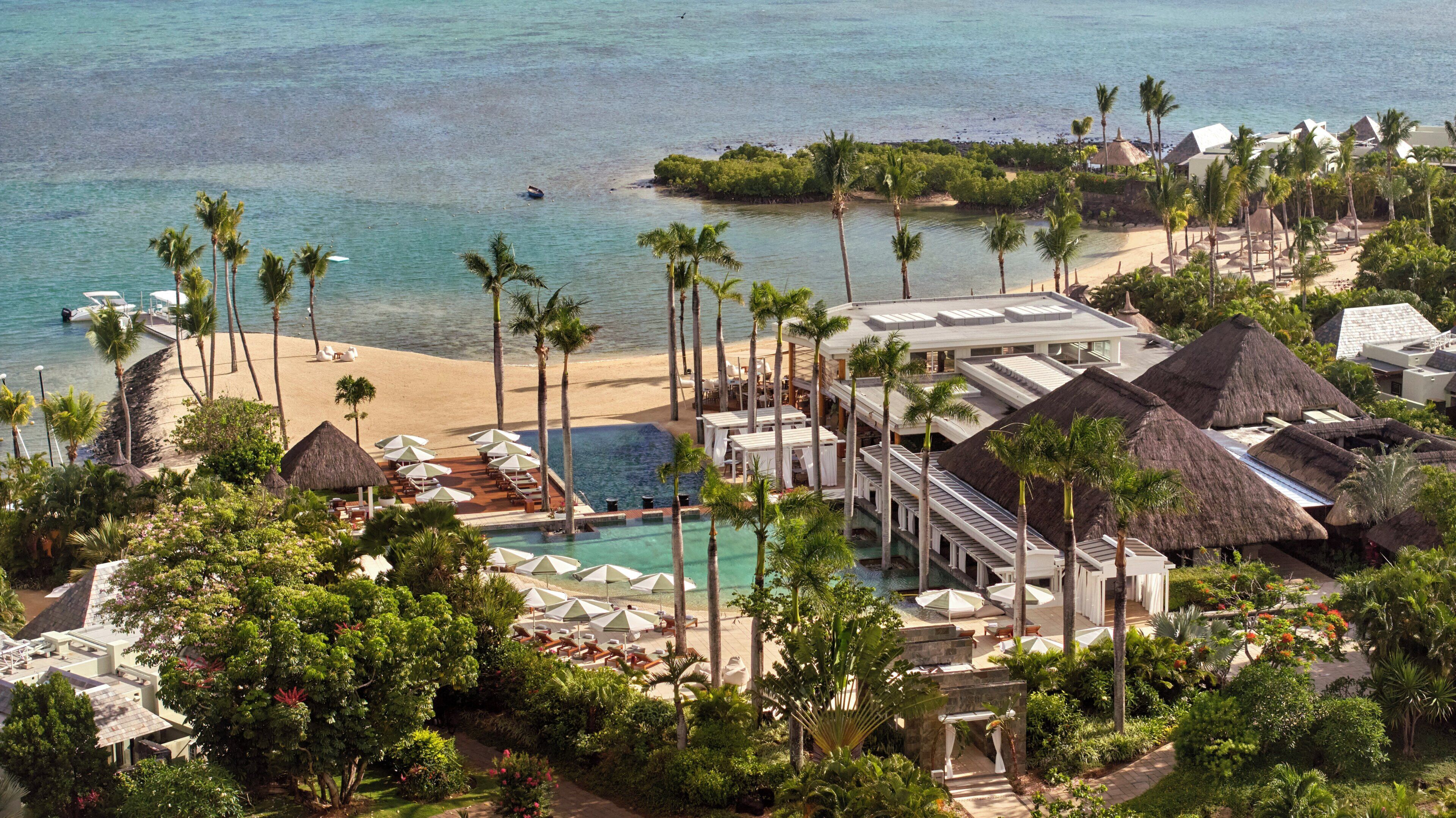 A resort with a pool, beach, and palm trees.
