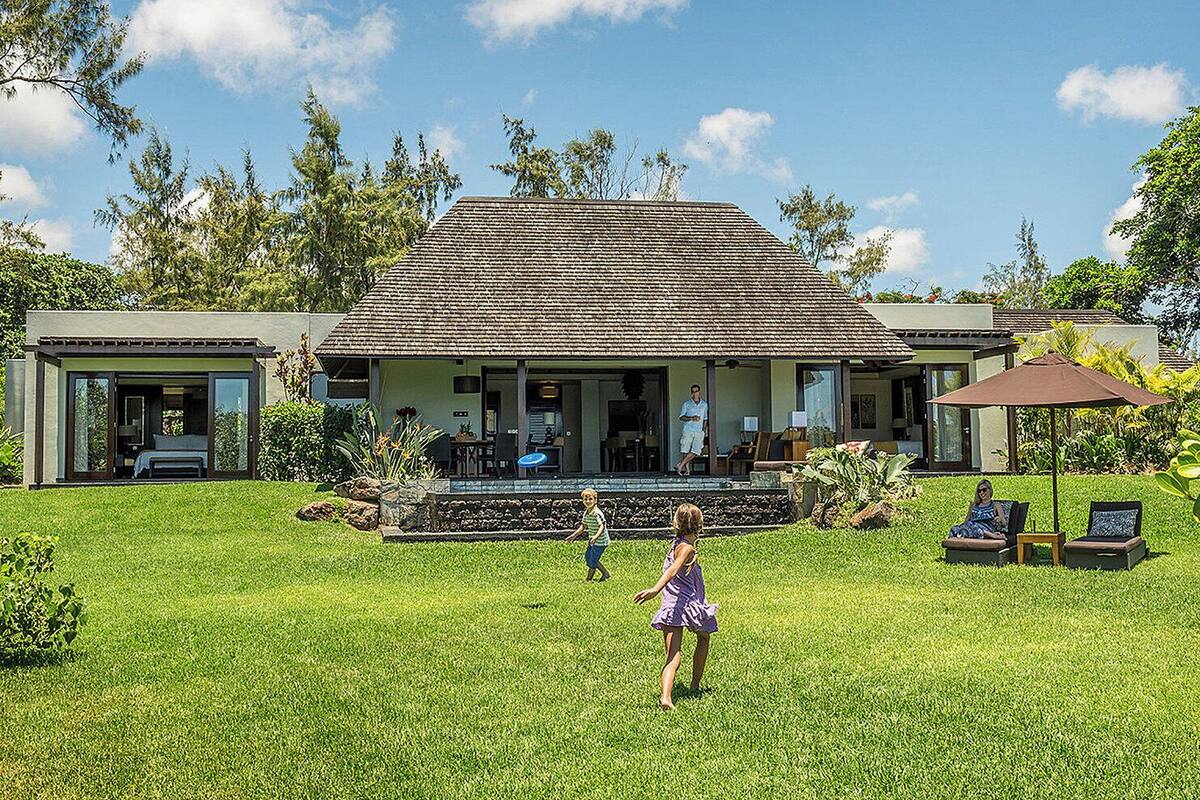 A modern house with a large lawn, a covered porch, and a pool.
