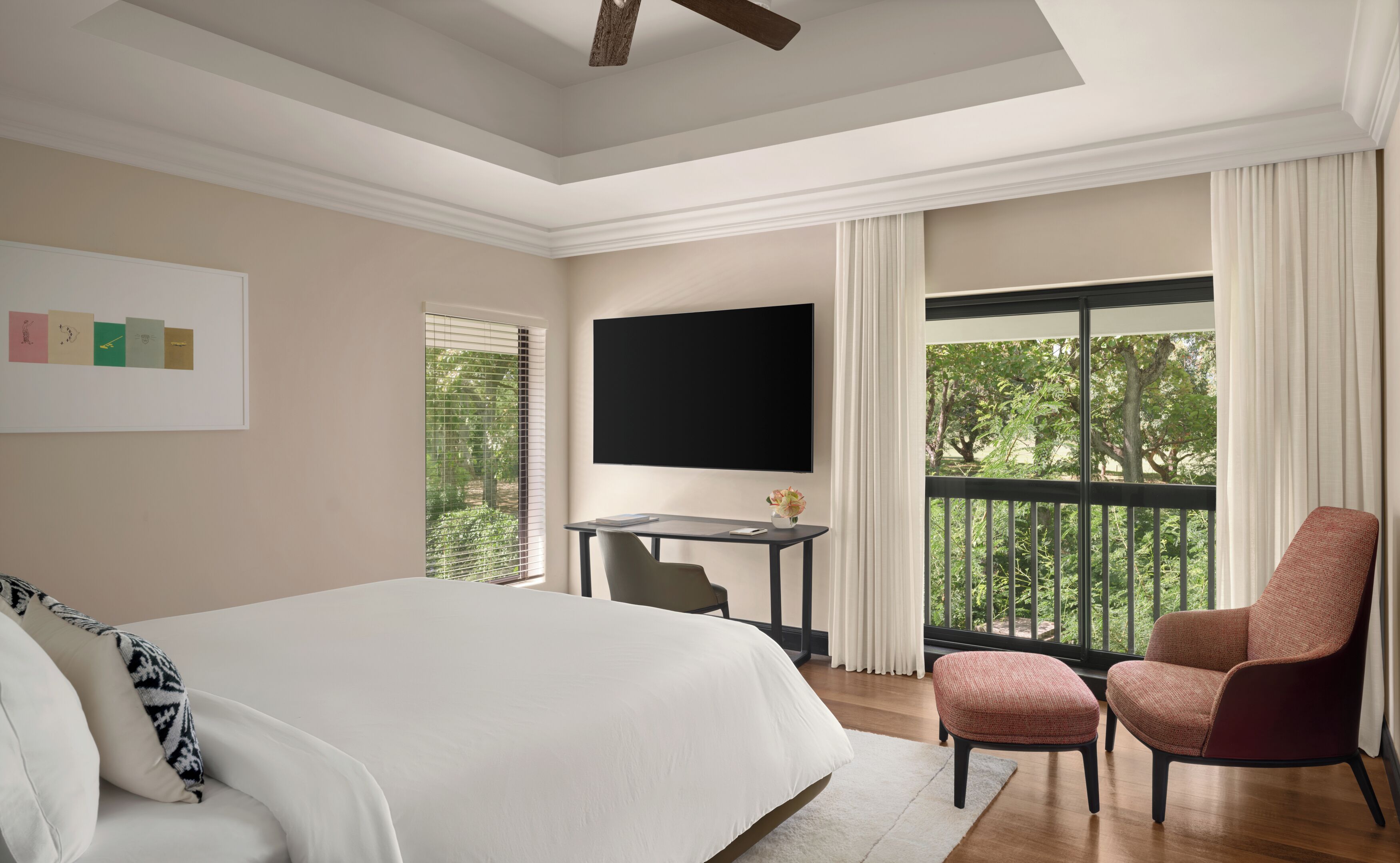A bedroom with a large bed, a TV, a desk, and a chair.