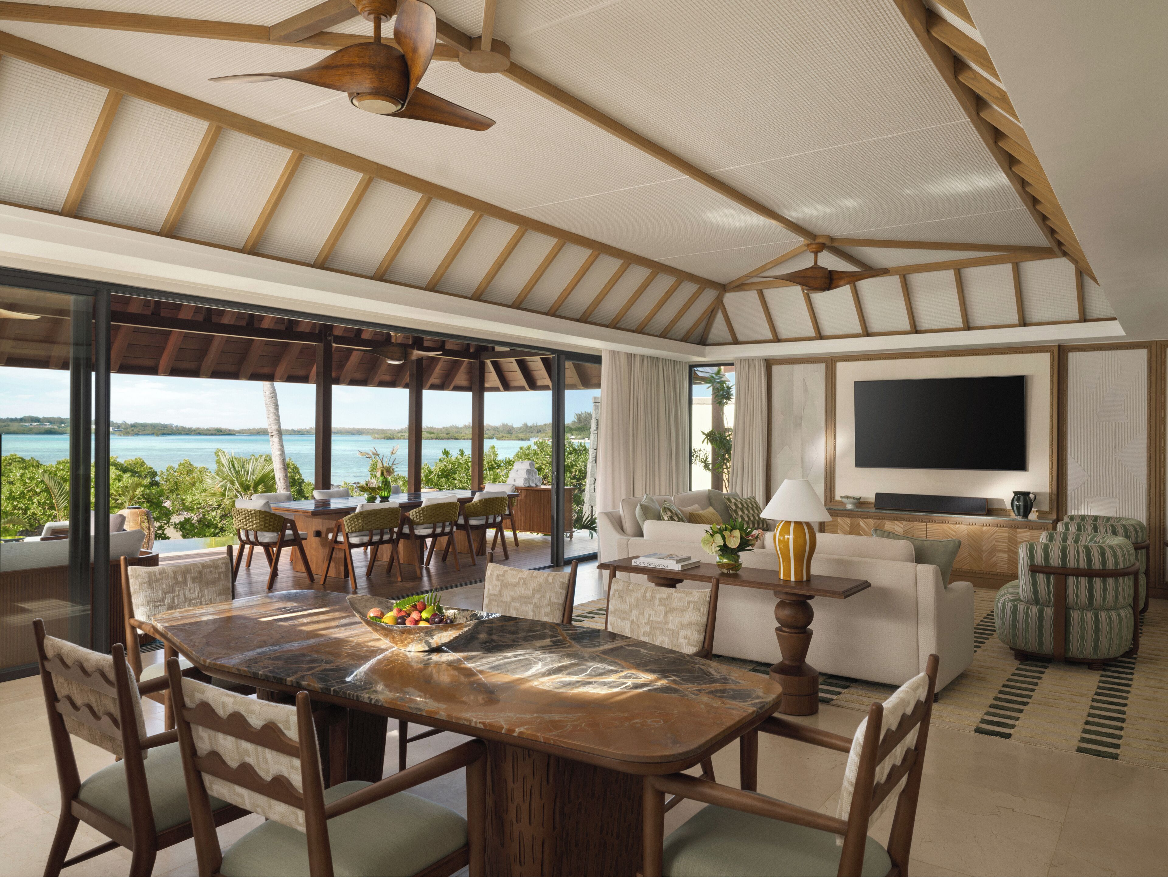 Una habitación amplia con una gran mesa de comedor, asientos cómodos, televisión y vistas al mar.