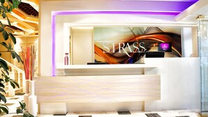 A reception area with a modern design, featuring a reception desk, a large abstract artwork, and a purple-lit ceiling. - Hotel Strass (Katerini)