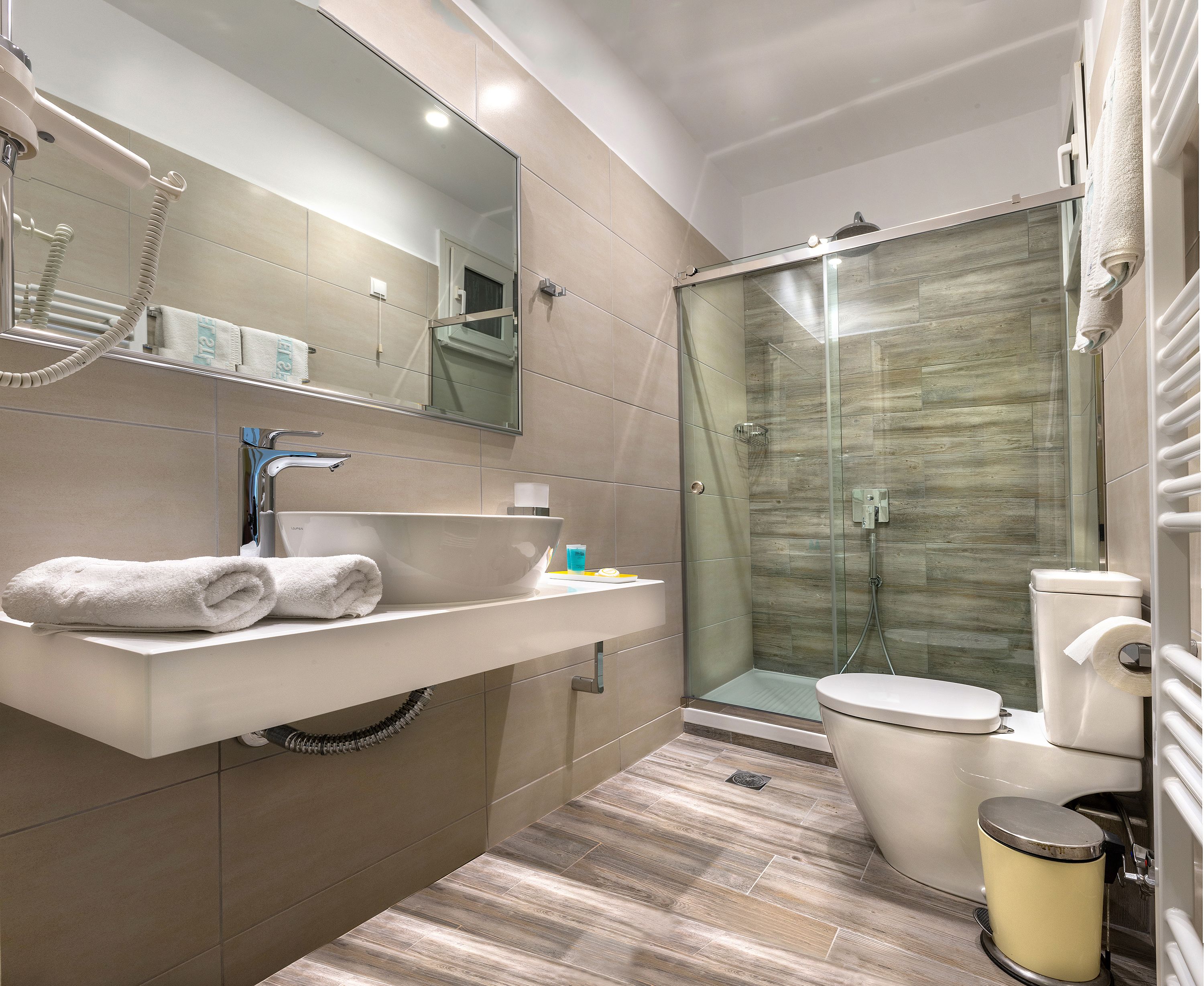 Un baño moderno con un lavabo grande, espejo y cabina de ducha de vidrio.