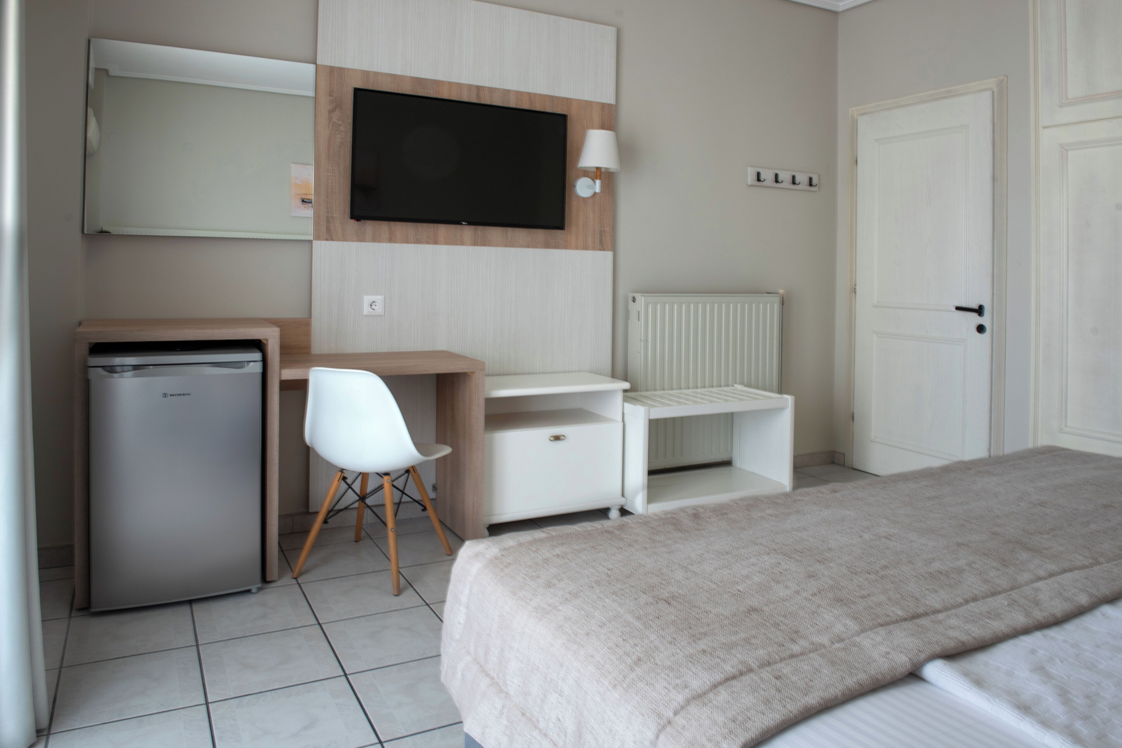 A bedroom with a bed, a desk, a chair, a television, and a wardrobe.