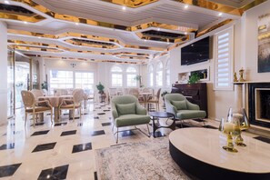 A spacious lobby with a checkered floor, multiple seating areas, and a fireplace.