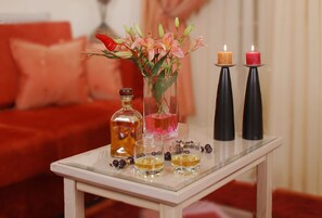 A table with a vase of flowers, two candles, a bottle, and glasses.