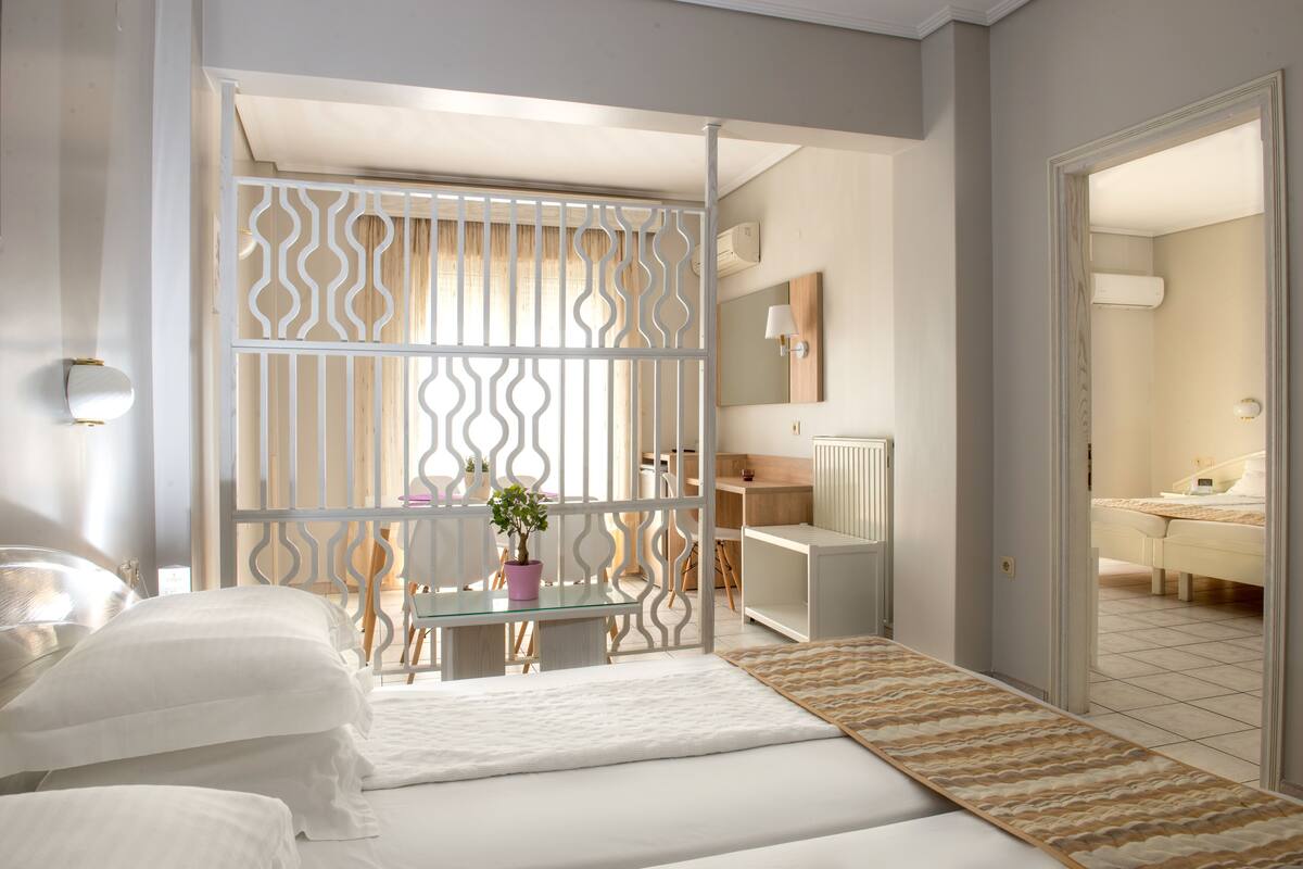 Un dormitorio con cama, mesita de noche, cómoda, espejo y planta en maceta.