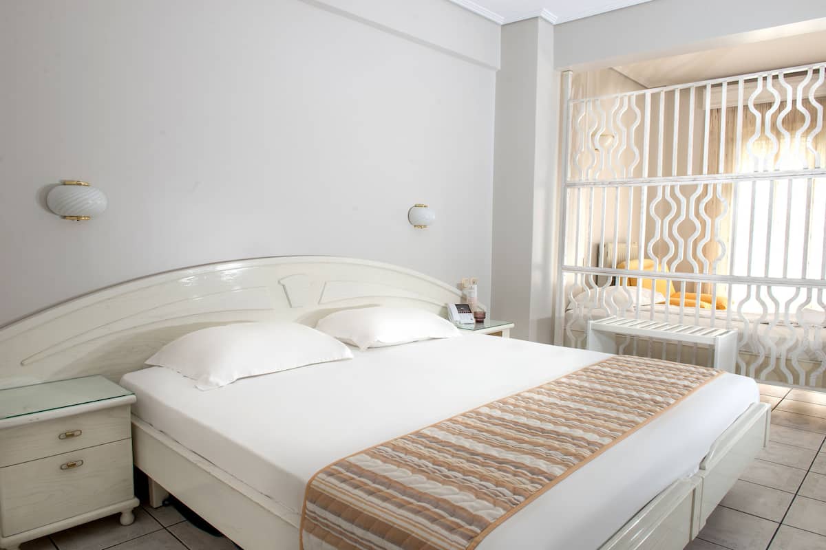 Una cama bien hecha con un edredón estampado, una mesita de noche con lámpara y un mueble auxiliar con cajones.