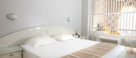 Una cama bien hecha con un edredón estampado, una mesita de noche con lámpara y un mueble auxiliar con cajones.
